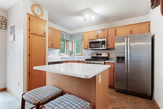 1580 9th Street Cir SE, Forest Lake, MN 55025 - kitchen with appliances with stainless steel finishes, light countertops, a kitchen island, a sink, and a textured ceiling