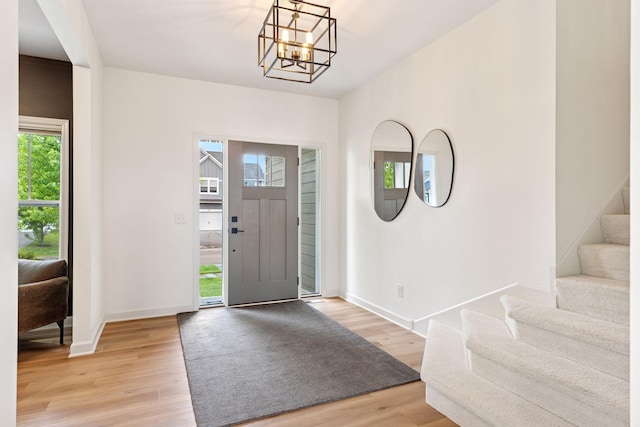 5175 White Star Ln, Woodbury, MN 55129 - foyer featuring light wood finished floors, a chandelier, stairs, and baseboards