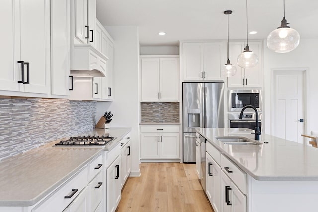 5175 White Star Ln, Woodbury, MN 55129 - kitchen with stainless steel appliances, a kitchen island with sink, recessed lighting, light wood-style floors, and a sink