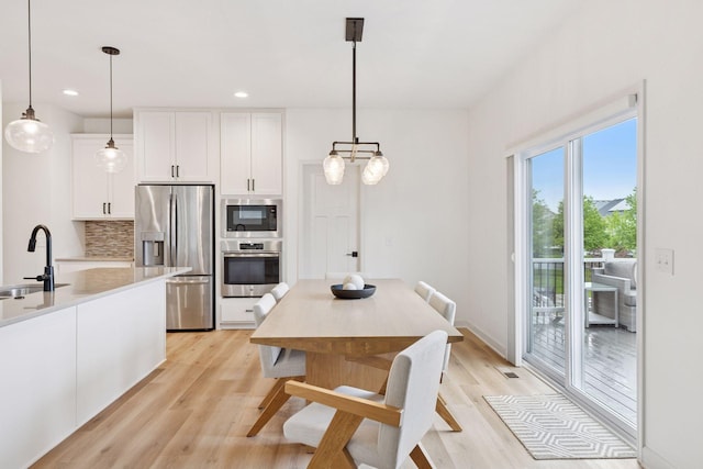5175 White Star Ln, Woodbury, MN 55129 - kitchen with stainless steel appliances, white cabinetry, light wood-style flooring, a sink, and recessed lighting