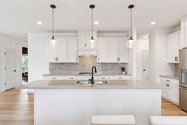 5175 White Star Ln, Woodbury, MN 55129 - kitchen with a sink, tasteful backsplash, light wood-style floors, an island with sink, and white cabinets