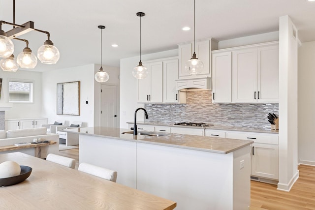 5175 White Star Ln, Woodbury, MN 55129 - kitchen featuring a sink, backsplash, light wood-style floors, stainless steel gas cooktop, and light countertops