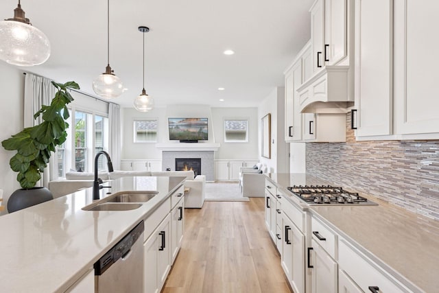 5175 White Star Ln, Woodbury, MN 55129 - kitchen featuring a sink, appliances with stainless steel finishes, light wood-type flooring, light countertops, and a glass covered fireplace