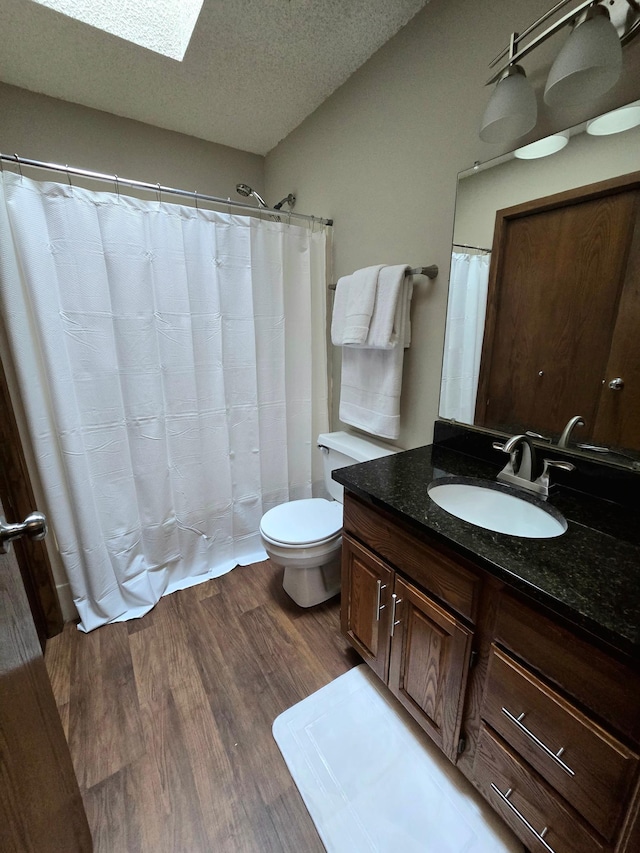 11173 Edgewood Cir N, Champlin, MN 55316 - bathroom featuring vanity, wood finished floors, toilet, a skylight, and a textured ceiling
