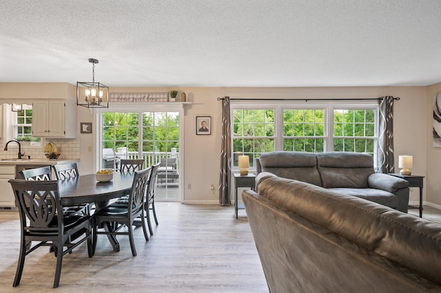 4142 Joppa Cir, Savage, MN 55378 - dining room with light wood-style flooring, a textured ceiling, baseboards, and a chandelier