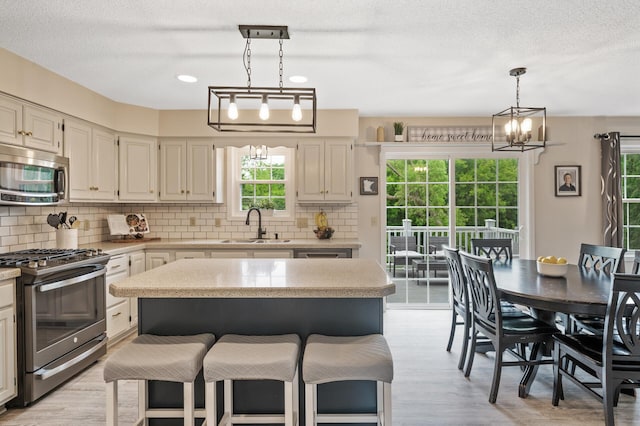 4142 Joppa Cir, Savage, MN 55378 - kitchen featuring appliances with stainless steel finishes, a sink, healthy amount of natural light, backsplash, and a textured ceiling