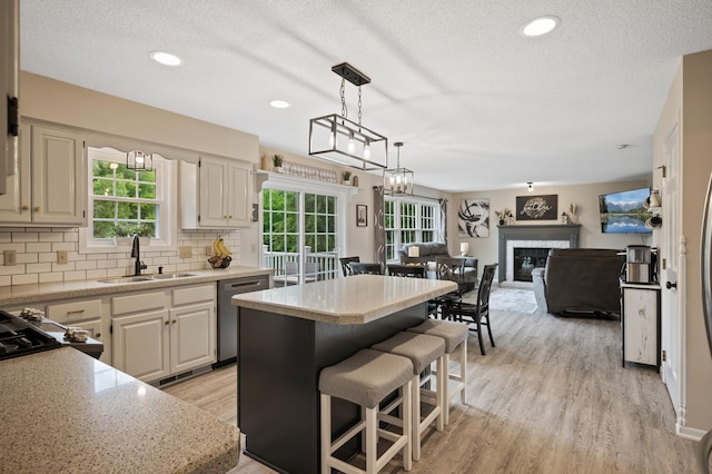 4142 Joppa Cir, Savage, MN 55378 - kitchen featuring dishwasher, a sink, a kitchen island, light wood-style flooring, and a textured ceiling