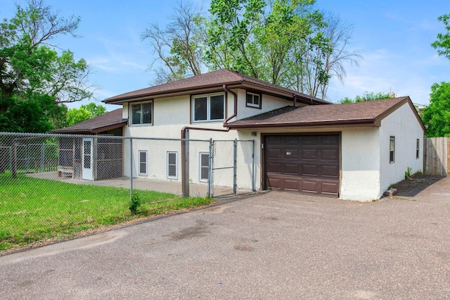 2125 White Bear Ave N, Maplewood, MN 55109 - tri-level home with stucco siding, a garage, a gate, asphalt driveway, and a shingled roof