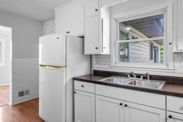 2125 White Bear Ave N, Maplewood, MN 55109 - kitchen with freestanding refrigerator, a sink, dark countertops, white cabinets, and wood finished floors