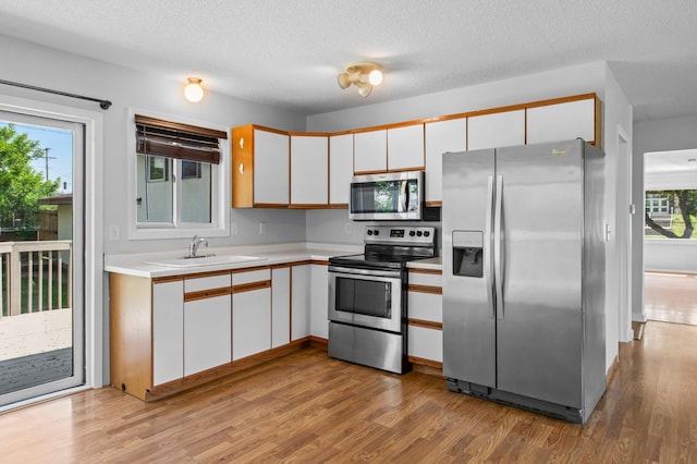 2125 White Bear Ave N, Maplewood, MN 55109 - kitchen with appliances with stainless steel finishes, a sink, light countertops, white cabinetry, and light wood-style floors