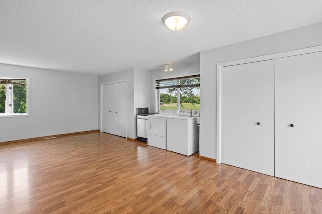 2125 White Bear Ave N, Maplewood, MN 55109 - unfurnished living room with separate washer and dryer, healthy amount of natural light, light wood-type flooring, and a textured ceiling
