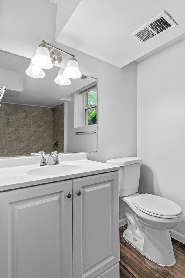2125 White Bear Ave N, Maplewood, MN 55109 - full bathroom with toilet, tiled shower, wood finished floors, vanity, and baseboards