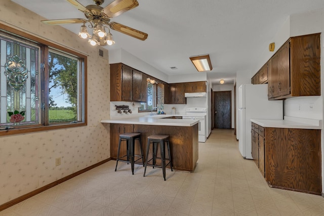 37875 600th Ave, Eden Valley, MN 55329 - kitchen featuring white appliances, light floors, under cabinet range hood, a peninsula, and light countertops