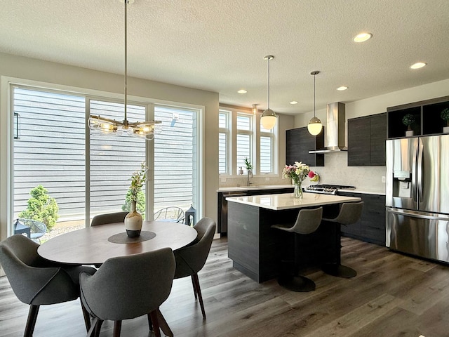 4848 161st St W, Lakeville, MN 55044 - kitchen featuring stainless steel appliances, wall chimney exhaust hood, light countertops, a kitchen island, and a textured ceiling