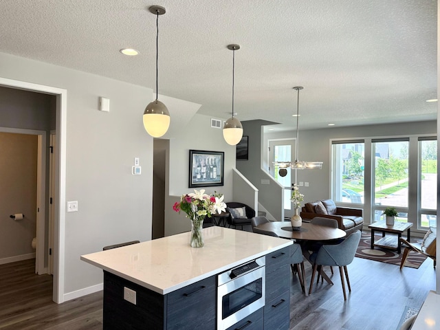 4848 161st St W, Lakeville, MN 55044 - kitchen featuring dark wood-style flooring, a textured ceiling, stainless steel microwave, light countertops, and hanging light fixtures