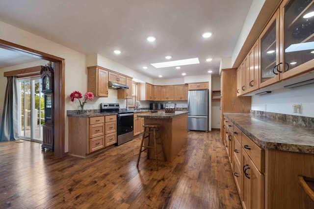 505 Superior Ave, Crosby, MN 56441 - kitchen featuring stainless steel appliances, under cabinet range hood, dark countertops, dark wood finished floors, and a center island
