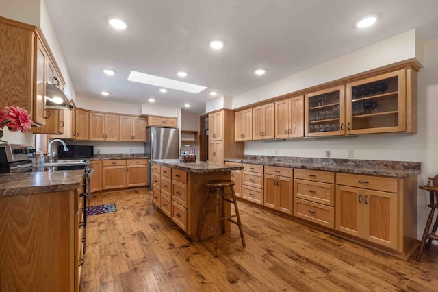505 Superior Ave, Crosby, MN 56441 - kitchen with a skylight, a kitchen breakfast bar, wood finished floors, freestanding refrigerator, and glass insert cabinets