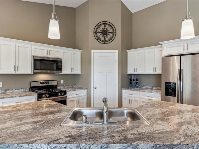 9308 Viking St, Brainerd, MN 56401 - kitchen featuring appliances with stainless steel finishes, vaulted ceiling, white cabinets, and decorative light fixtures