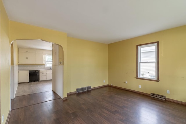 509 8th Ave SE, Waseca, MN 56093 - spare room featuring arched walkways, dark wood-style floors, and baseboards