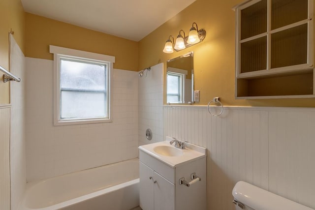 509 8th Ave SE, Waseca, MN 56093 - bathroom featuring toilet, vanity, bathtub / shower combination, and a wainscoted wall