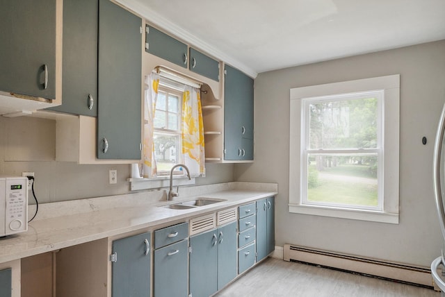 517 Birch Ave, Moose Lake, MN 55767 - kitchen featuring a baseboard radiator, a sink, white microwave, light wood-type flooring, and light stone countertops