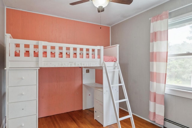 517 Birch Ave, Moose Lake, MN 55767 - unfurnished bedroom featuring multiple windows, a baseboard heating unit, wood finished floors, crown molding, and wooden walls