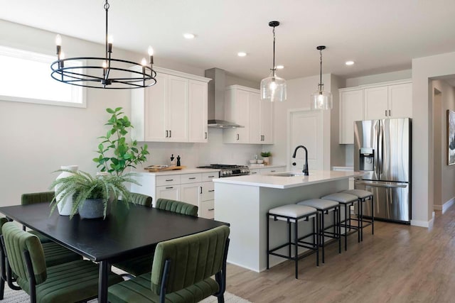 12443 Drayton Trl, Apple Valley, MN 55124 - kitchen with appliances with stainless steel finishes, wall chimney range hood, a sink, a center island with sink, and a breakfast bar area