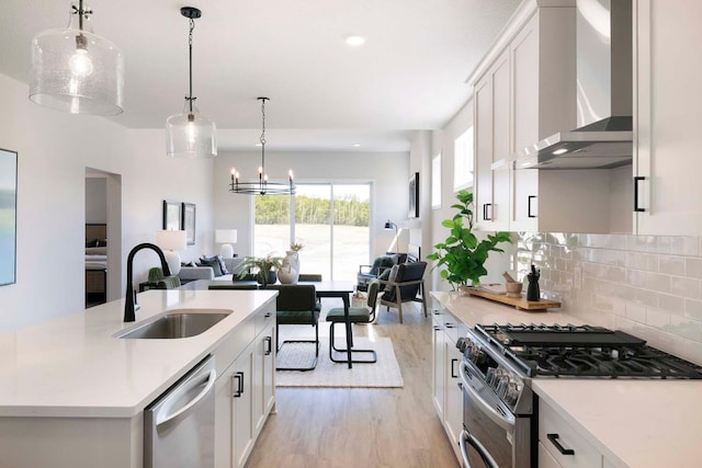 12443 Drayton Trl, Apple Valley, MN 55124 - kitchen featuring appliances with stainless steel finishes, wall chimney exhaust hood, a sink, open floor plan, and light wood-style floors