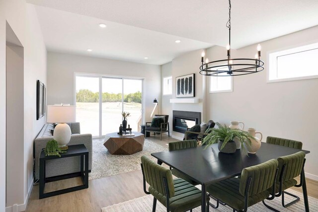 12443 Drayton Trl, Apple Valley, MN 55124 - dining area featuring light wood-style flooring, a chandelier, a glass covered fireplace, recessed lighting, and baseboards