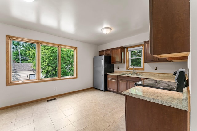 1809 Penn Ave N, Minneapolis, MN 55411 - kitchen featuring freestanding refrigerator, a sink, black range with electric stovetop, light countertops, and baseboards