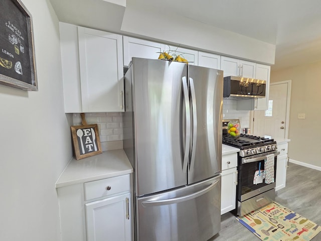 4106 Woodbine Ln N, Brooklyn Center, MN 55429 - kitchen featuring stainless steel appliances, light countertops, white cabinetry, light wood finished floors, and decorative backsplash