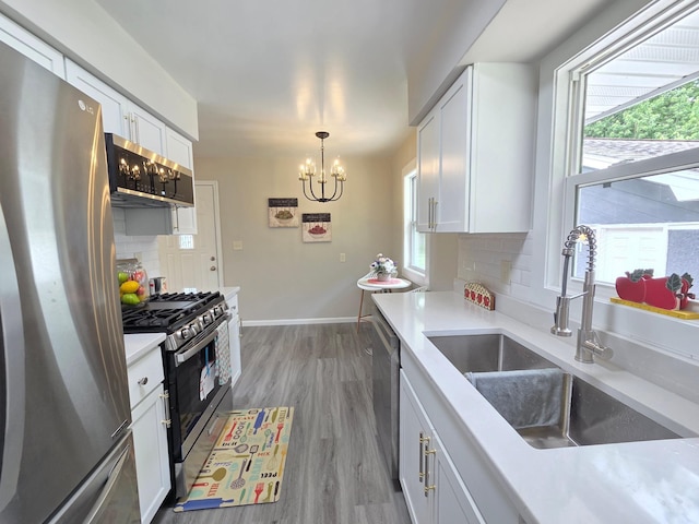 4106 Woodbine Ln N, Brooklyn Center, MN 55429 - kitchen with stainless steel appliances, a sink, decorative backsplash, a chandelier, and white cabinets