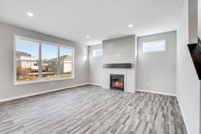16296 Fairoaks Ave N, Hugo, MN 55038 - unfurnished living room with wood finished floors, plenty of natural light, a fireplace, baseboards, and recessed lighting