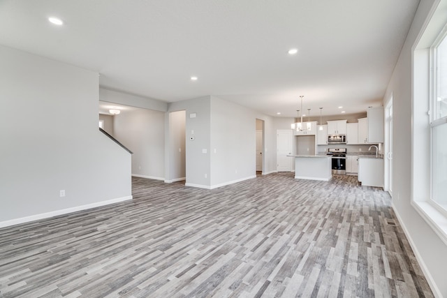 16296 Fairoaks Ave N, Hugo, MN 55038 - unfurnished living room featuring light wood finished floors, recessed lighting, baseboards, a sink, and a chandelier