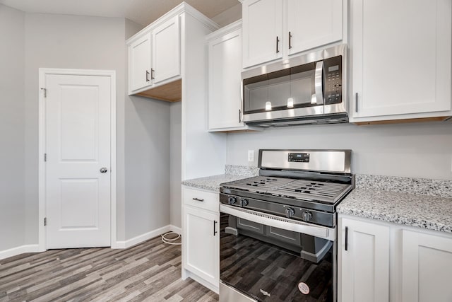 16296 Fairoaks Ave N, Hugo, MN 55038 - kitchen featuring stainless steel appliances, light wood finished floors, white cabinetry, baseboards, and light stone counters