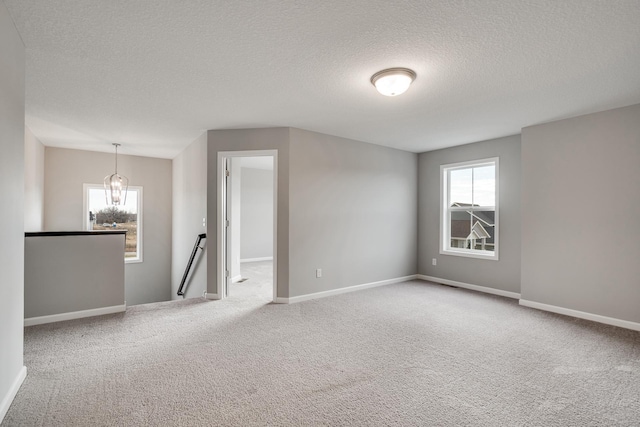 16296 Fairoaks Ave N, Hugo, MN 55038 - empty room with a textured ceiling, plenty of natural light, carpet floors, a chandelier, and baseboards