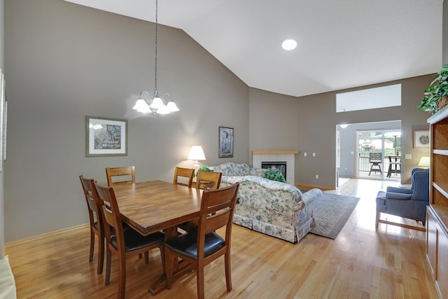 10777 181st Cir NW, Elk River, MN 55330 - dining area featuring a fireplace, high vaulted ceiling, a chandelier, and light wood-type flooring