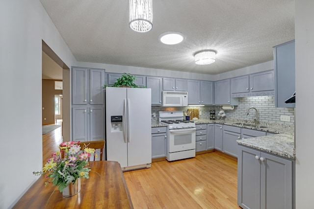 10777 181st Cir NW, Elk River, MN 55330 - kitchen with white appliances, gray cabinetry, light wood-style floors, decorative backsplash, and a textured ceiling