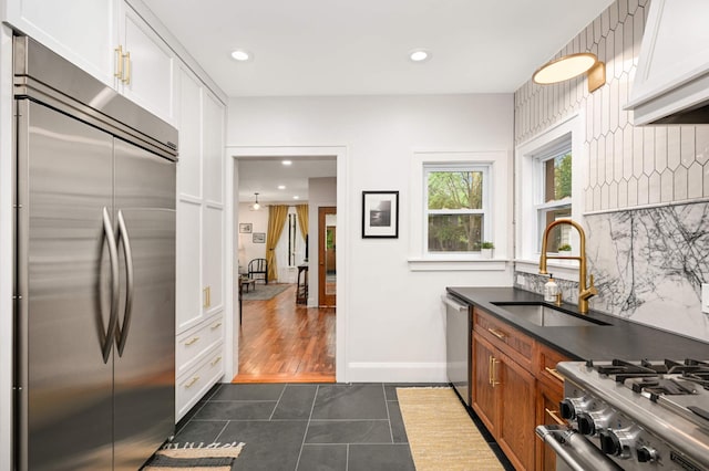 2916 26th St, Minneapolis, MN 55406 - kitchen with stainless steel appliances, dark tile patterned floors, decorative backsplash, dark countertops, and white cabinets
