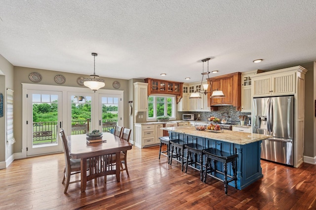 1755 Chateau Way, Minnetrista, MN 55359 - kitchen with stainless steel appliances, a textured ceiling, glass insert cabinets, a center island, and tasteful backsplash