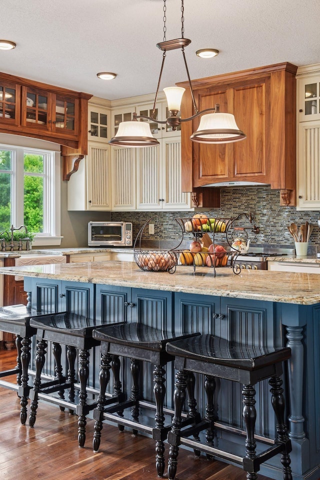 1755 Chateau Way, Minnetrista, MN 55359 - kitchen with a kitchen bar, wood finished floors, light stone countertops, tasteful backsplash, and a textured ceiling