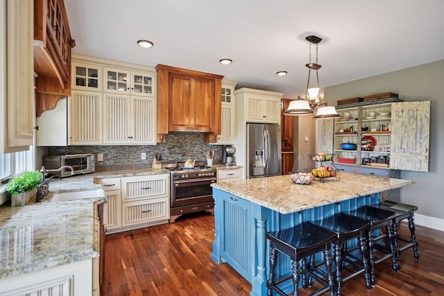 1755 Chateau Way, Minnetrista, MN 55359 - kitchen featuring appliances with stainless steel finishes, dark wood-style flooring, backsplash, a kitchen island, and light stone countertops