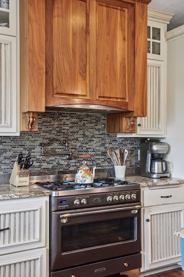 1755 Chateau Way, Minnetrista, MN 55359 - kitchen featuring range with two ovens, decorative backsplash, light stone counters, and glass insert cabinets