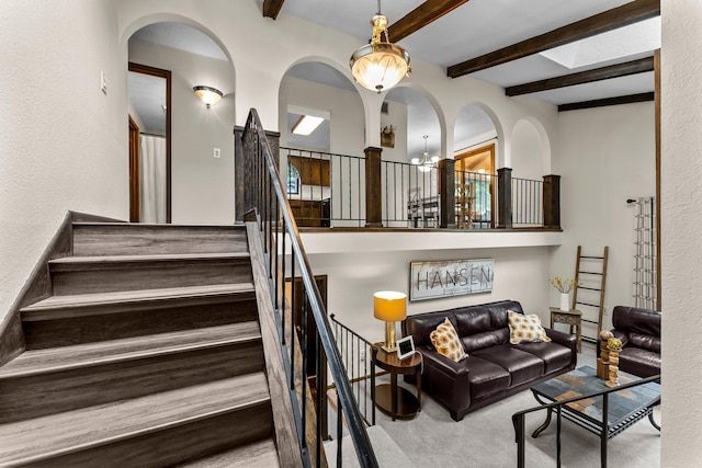 8409 Knollwood Dr, Mounds View, MN 55112 - carpeted living room featuring a textured wall, beam ceiling, a chandelier, and stairway