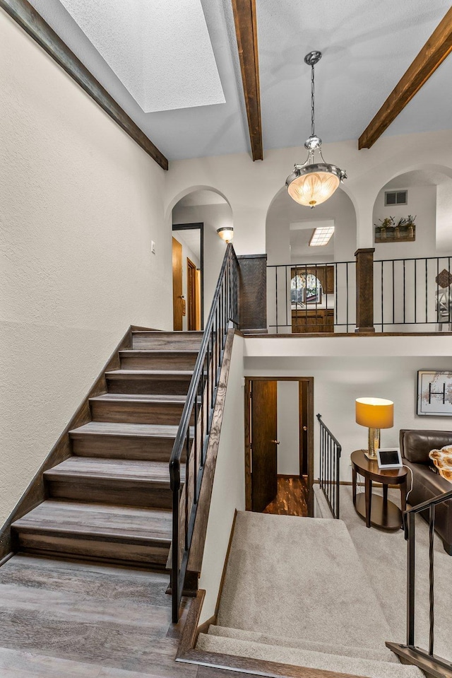 8409 Knollwood Dr, Mounds View, MN 55112 - stairs with beam ceiling, arched walkways, a skylight, and a high ceiling