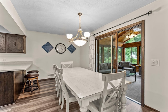 8409 Knollwood Dr, Mounds View, MN 55112 - dining space with wood finished floors, baseboards, a chandelier, a bar, and a textured ceiling