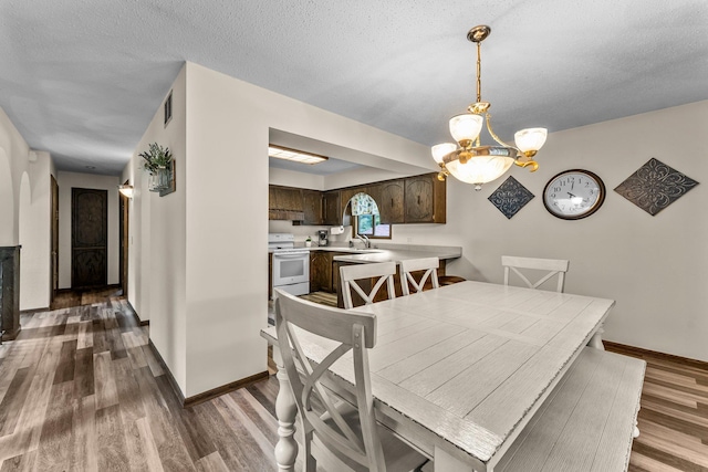 8409 Knollwood Dr, Mounds View, MN 55112 - dining space featuring a chandelier, dark wood finished floors, baseboards, and a textured ceiling