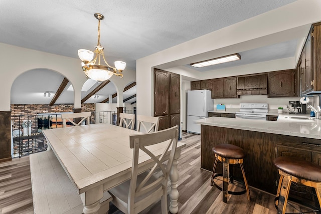 8409 Knollwood Dr, Mounds View, MN 55112 - dining space with light wood finished floors, a chandelier, arched walkways, and a textured ceiling