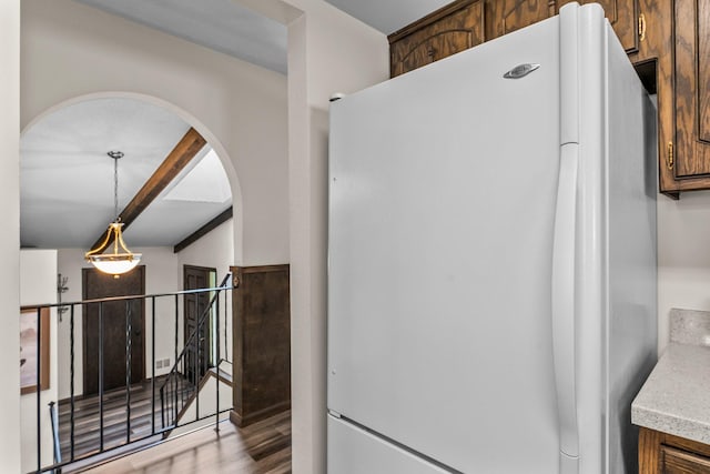 8409 Knollwood Dr, Mounds View, MN 55112 - kitchen featuring freestanding refrigerator, arched walkways, wood finished floors, light countertops, and pendant lighting