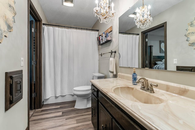 8409 Knollwood Dr, Mounds View, MN 55112 - ensuite bathroom with a chandelier, wood finished floors, vanity, toilet, and a textured ceiling